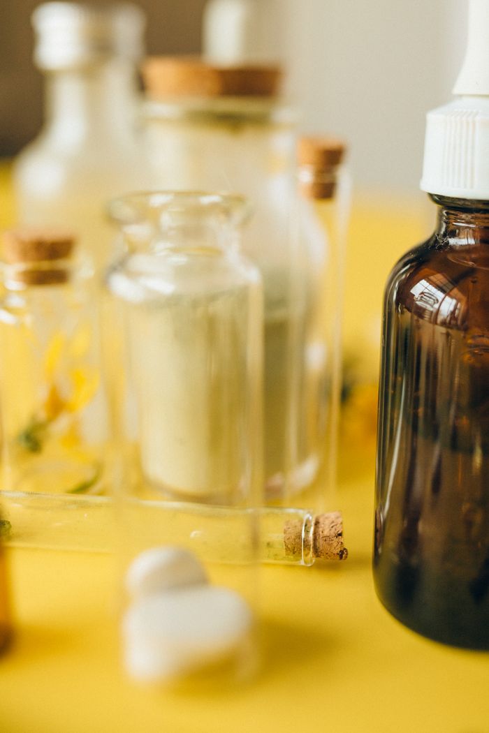 Various glass bottles and tablets on a bright yellow background, highlighting alternative medicine.